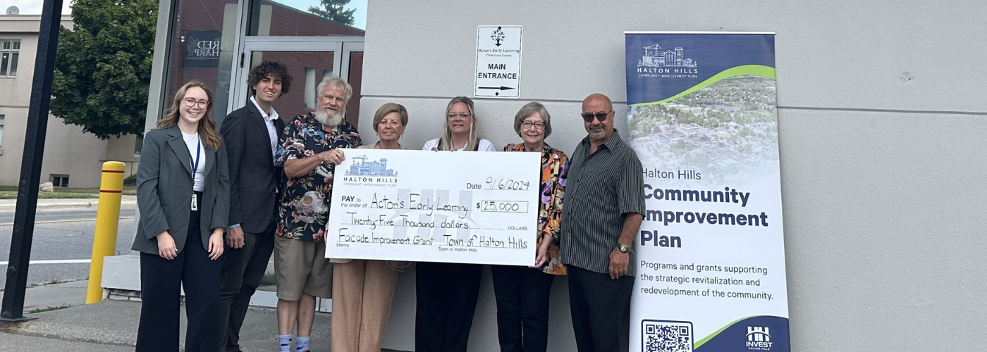 people standing with large cheque in front of building