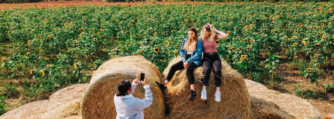 Girls sitting on a hay bail going to getting their picture taken