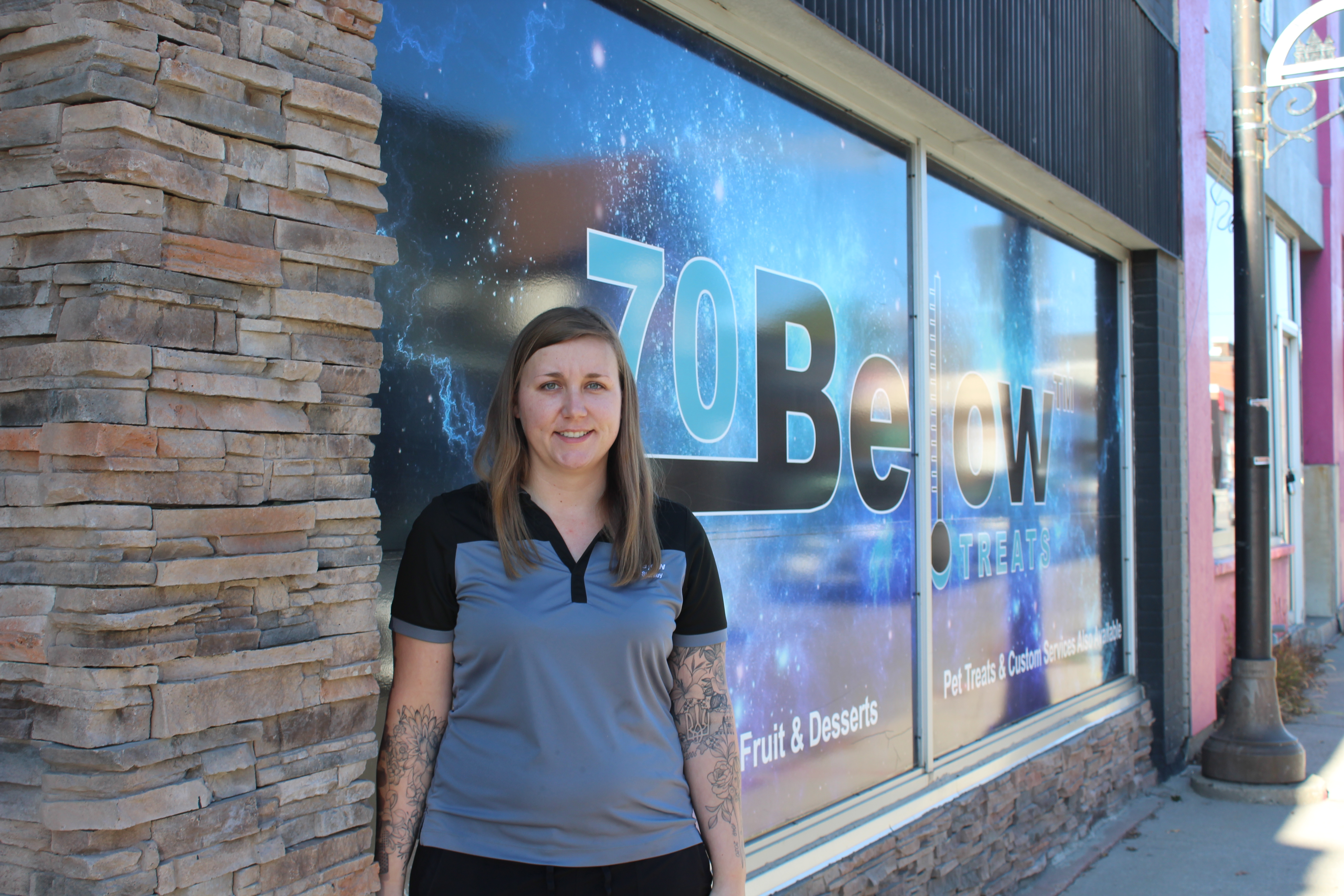 Women standing in front of store front in a downtown. 